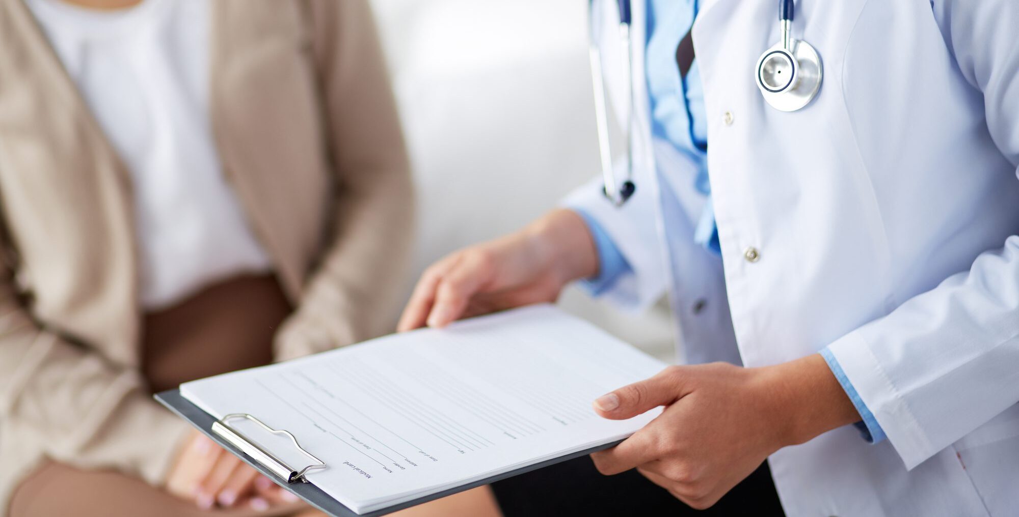 Female Doctor Holding Application Form While Consulting Patient